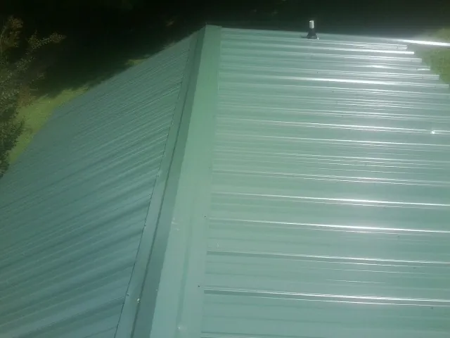 New green metal panels meeting at the ridge of a roof — Flat Roof Repair work by our crew in Richards