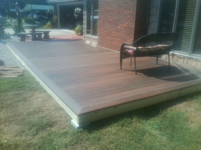 New wood deck and wicker chair beside a brick house in Richards