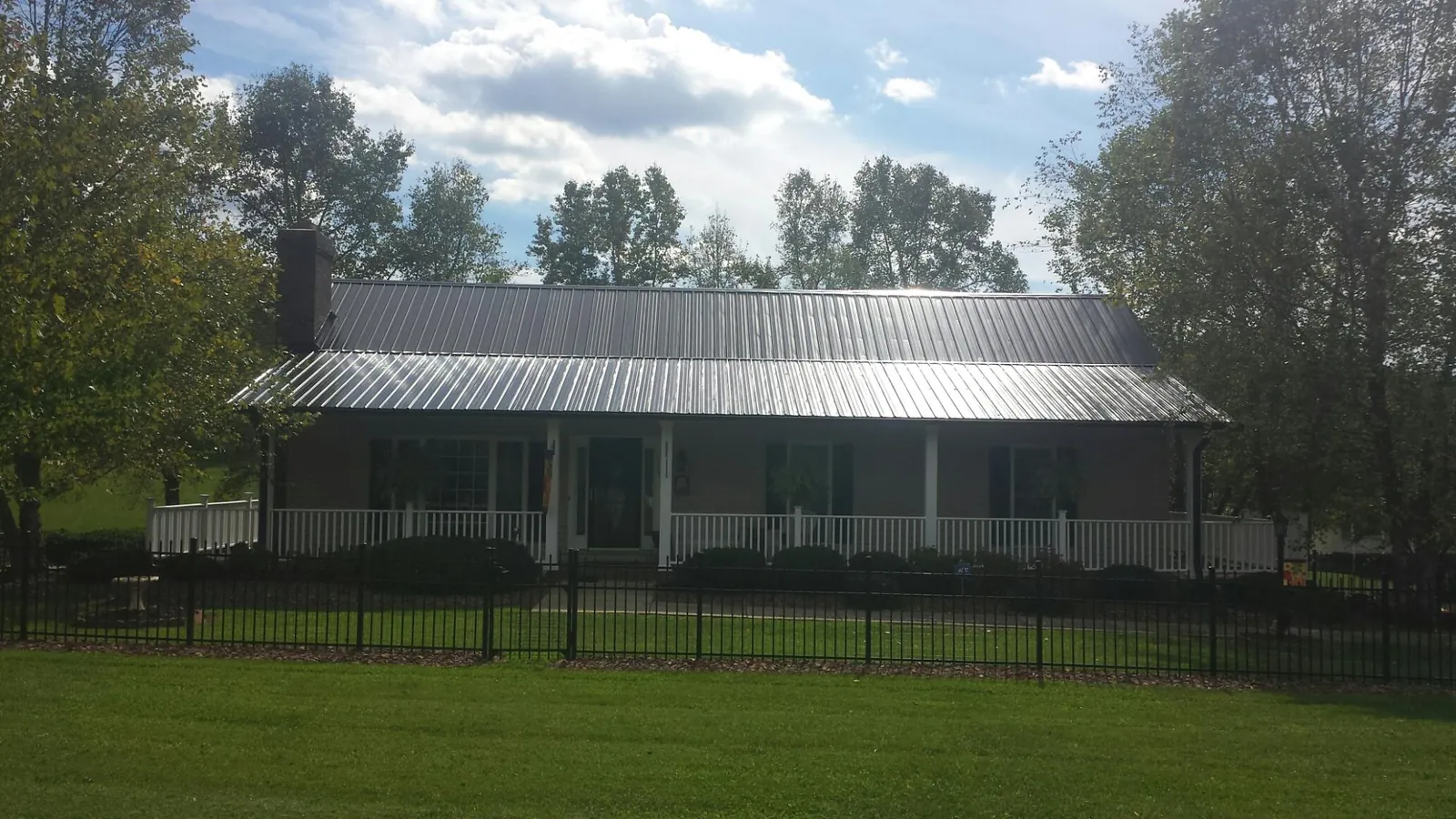 Gray metal roof on a brick ranch with a full width front porch — Gutter Guard Installation work by our crew in Richards