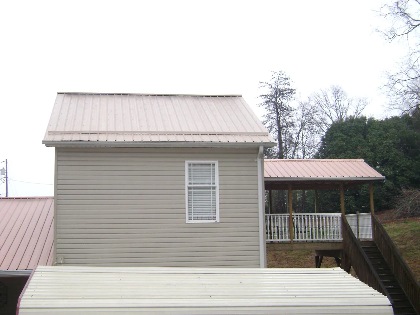 Tan metal roofs on a two story addition and attached porch, from a Roof Replacement job in Richards